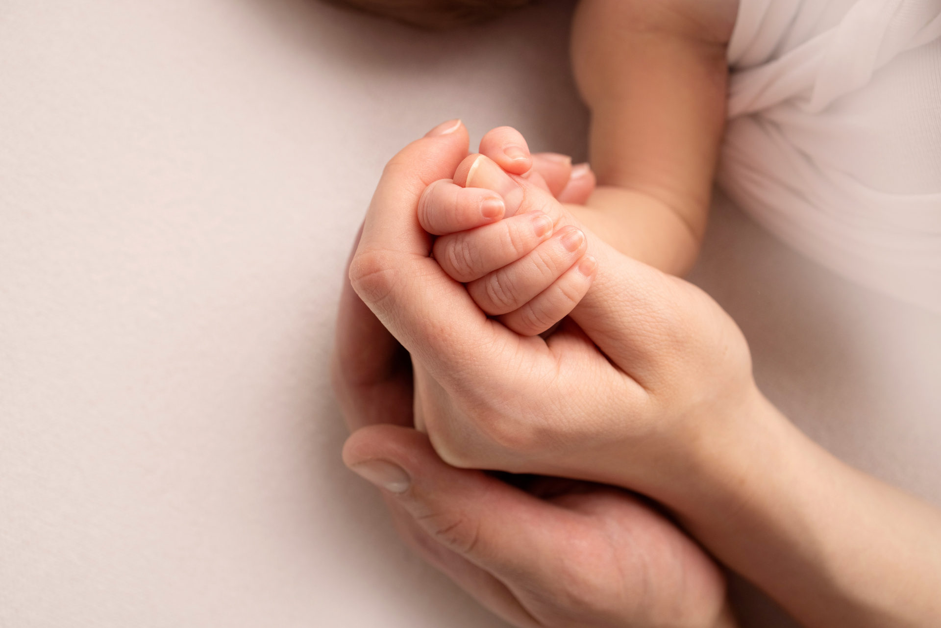 A close-up of a sleeping newborn's hand in the hands of its mother and father. The newborn's tiny fingers. The family is holding hands. Studio macro photography. Concepts of family and love. A close-up of a sleeping newborn's hand in the hands of its mother and father. The newborn's tiny fingers. The family is holding hands. Studio macro photography. Concepts of family and love.
