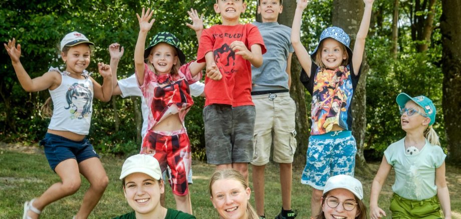 Lächelnde und jubelnde Kinder; im Vordergrund die Betreuerinnen