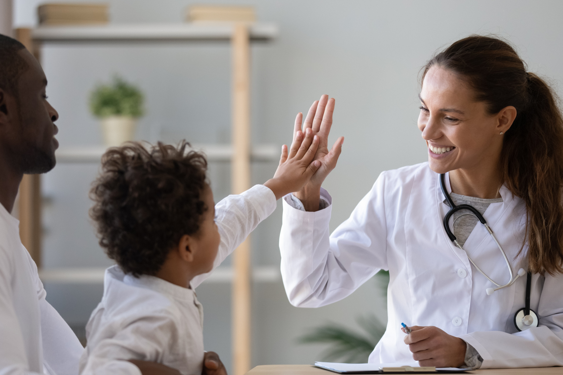 Smiling female doctor give high five to little biracial patient Smiling female doctor give high five to little biracial patient